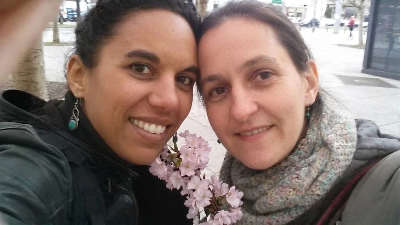 Laurence et Nancy Bon, joue contre joue, souriantes, devant des fleurs de cerisier.