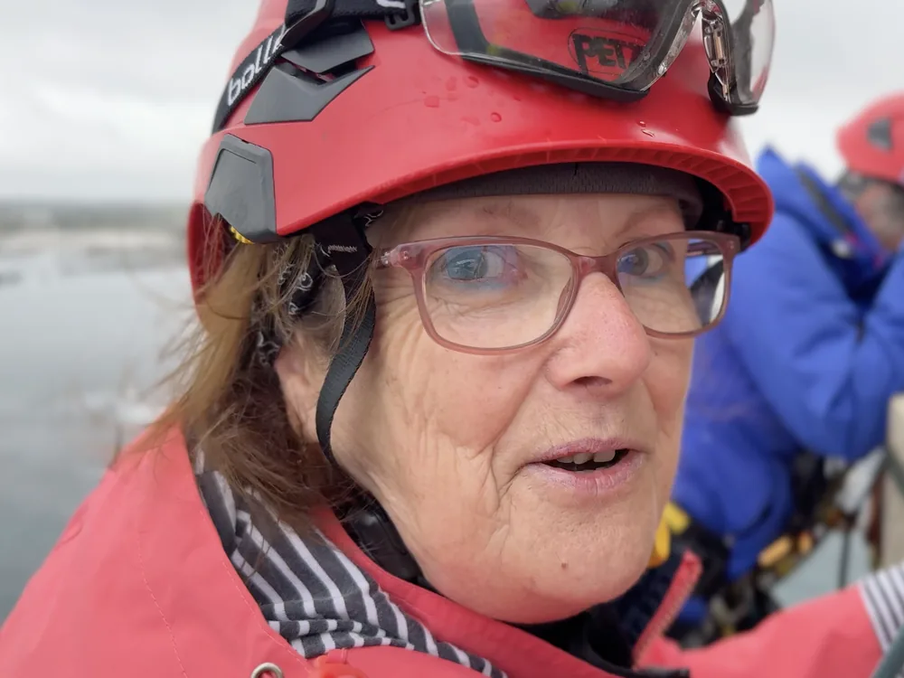 Portrait d'Anne, Athlète du Vertige : casque rouge, veste rouge et lunettes, le regard tourné vers la caméra.