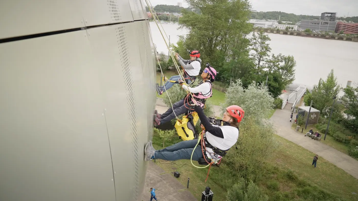 Trois personnes descendent en rappel le long de la façade de la Cité du Vin, à Bordeaux.